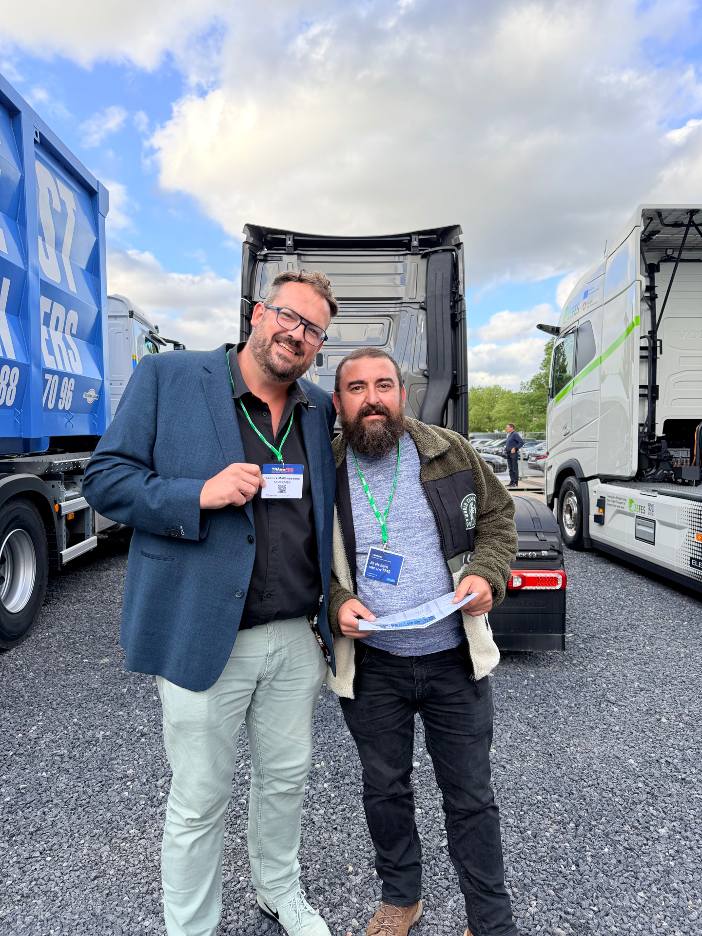 Mahmut ÖZ and Yannick Mattheessens representing MGM-EMEA at Transpro 2026 in Waregem Expo, Belgium, standing between trucks and commercial vehicles